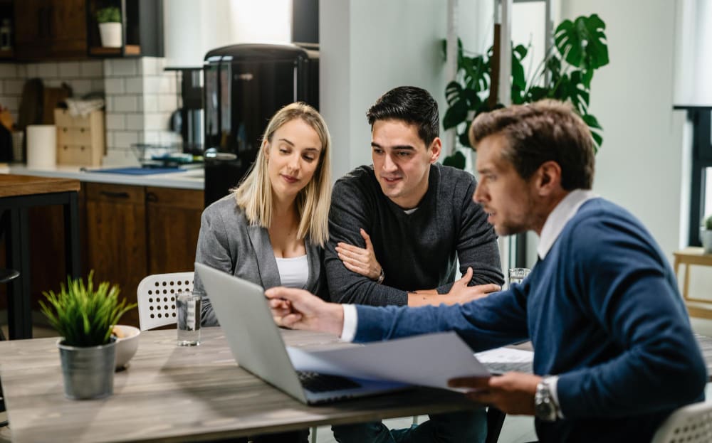young couple real estate agent using laptop while going through housing plan meeting